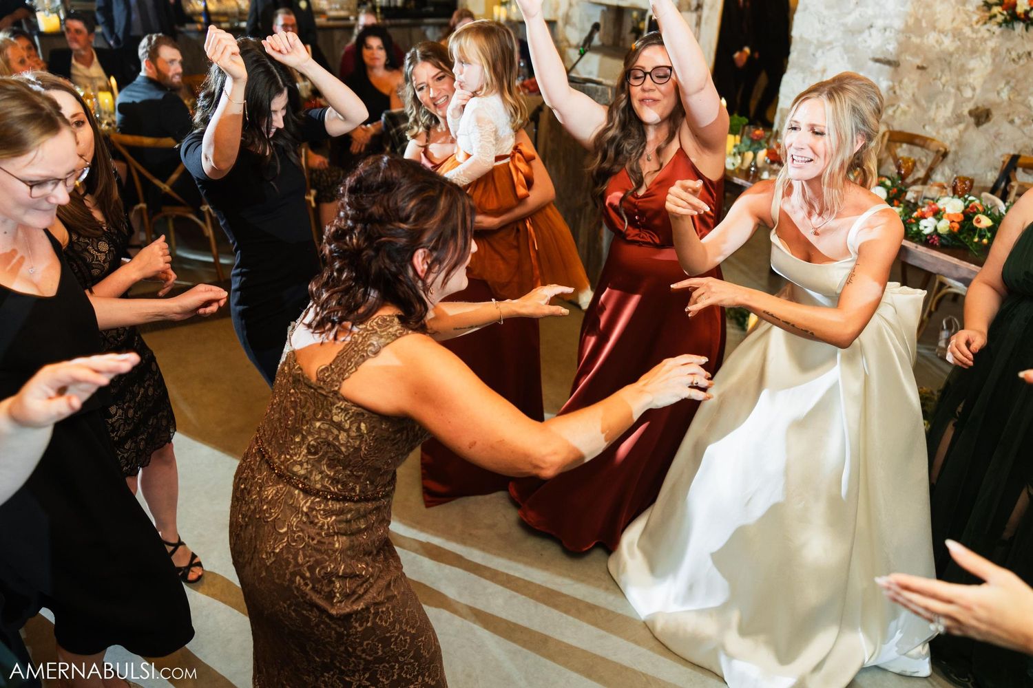 Wedding guests dancing and celebrating on dance floor during reception.
