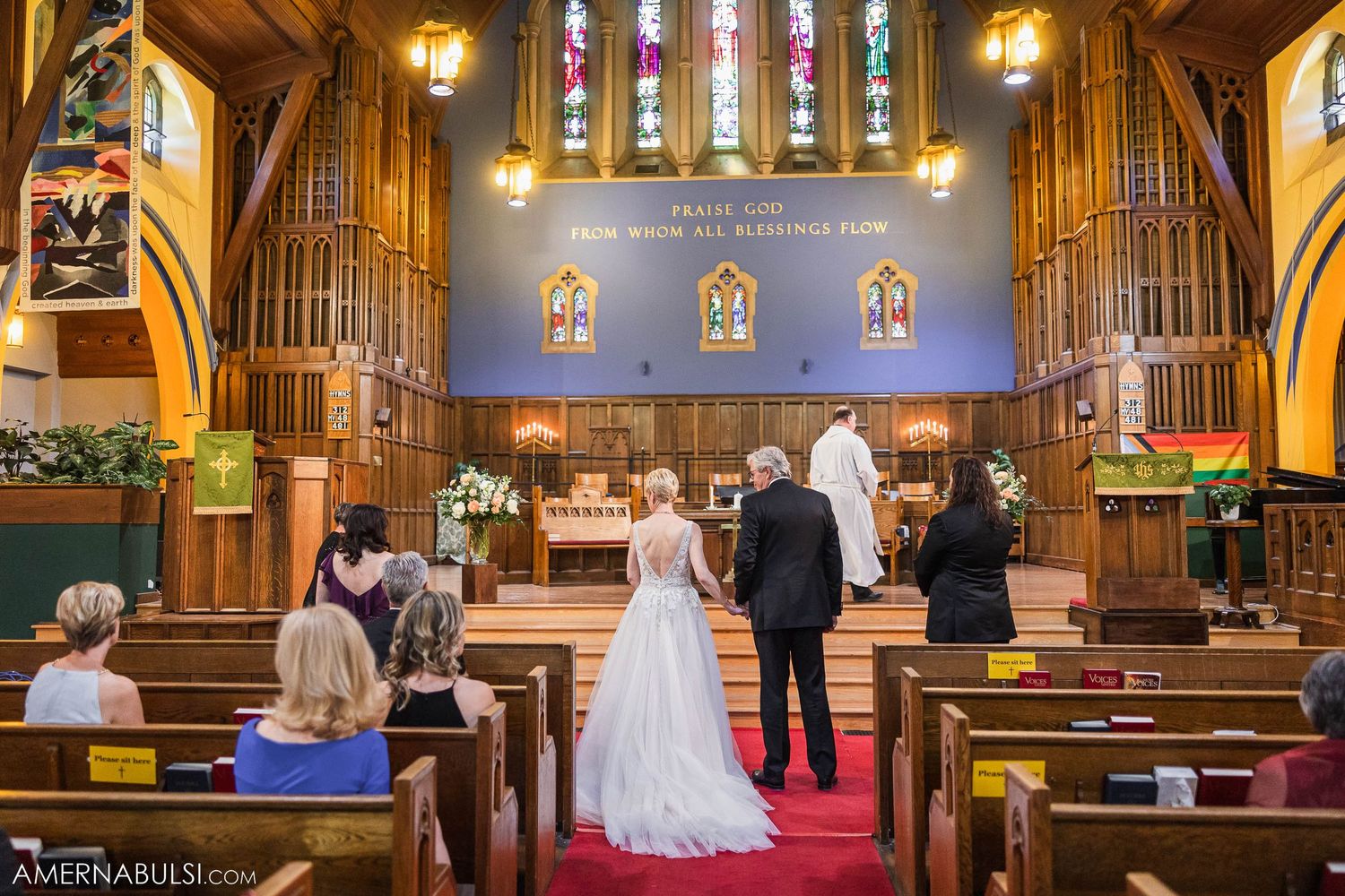 Wedding ceremony taking place in a beautiful church with stained glass windows and wooden pipe organ.