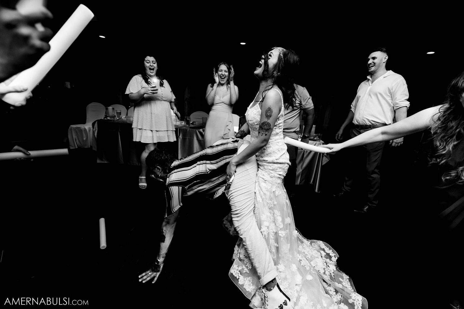Energetic dance party scene at a wedding reception in black and white with people dancing.