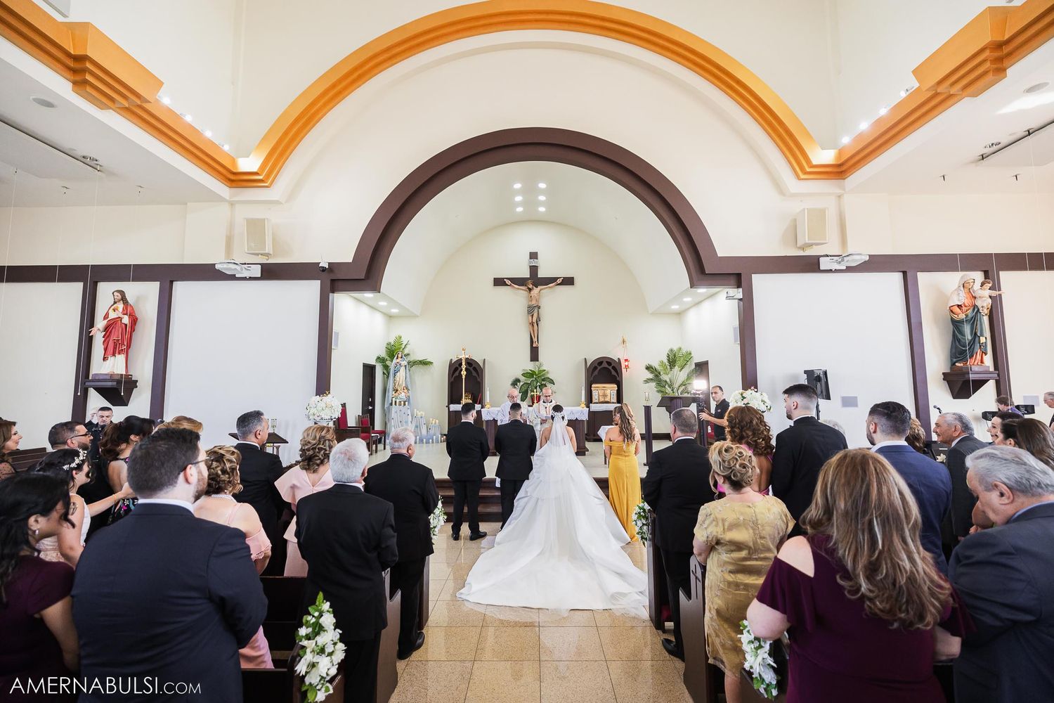 A traditional Catholic church wedding ceremony with guests watching the proceedings.
