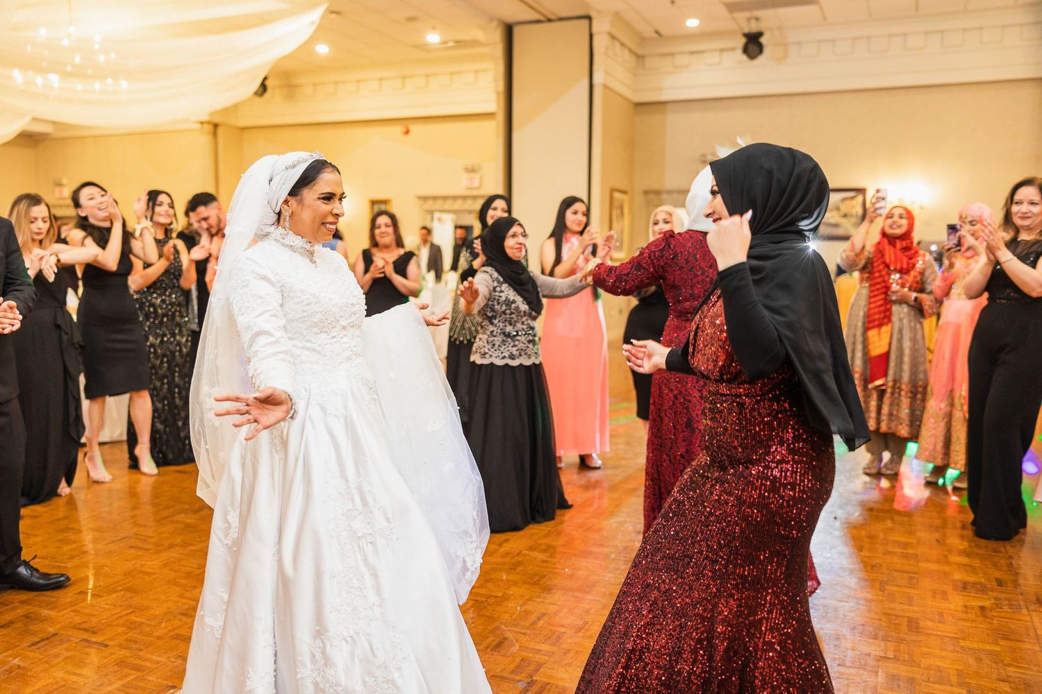 Wedding celebration featuring traditional dance moves on a wooden ballroom floor.