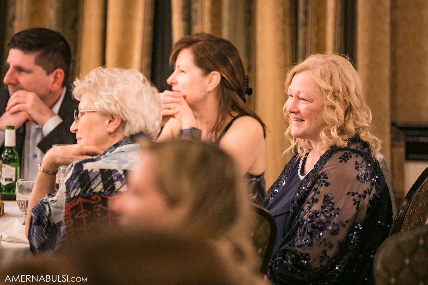 Wedding guests mingle and socialize during an elegant reception in a warmly lit banquet hall.