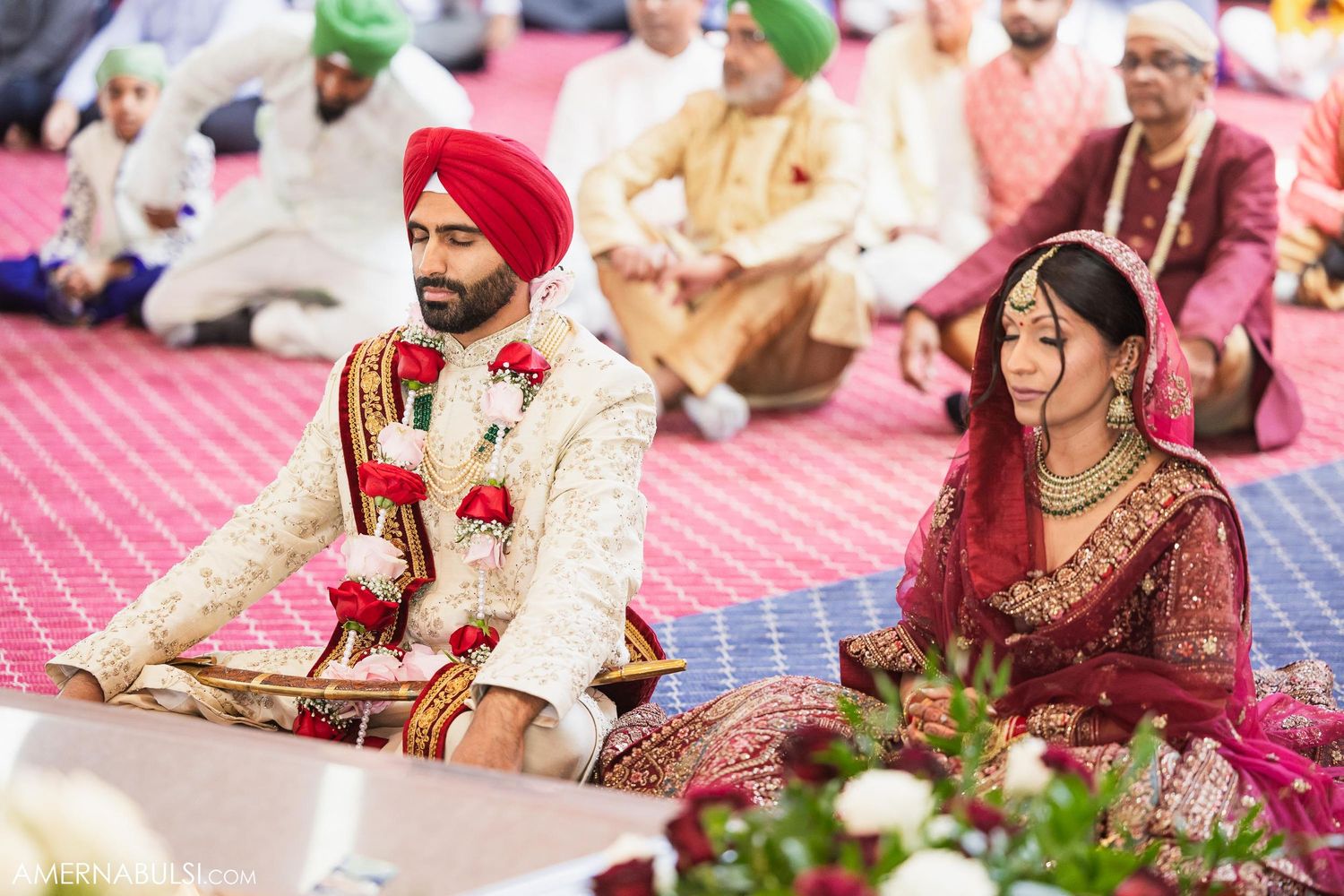 Couple participating in traditional Sikh wedding ceremony on decorated altar.