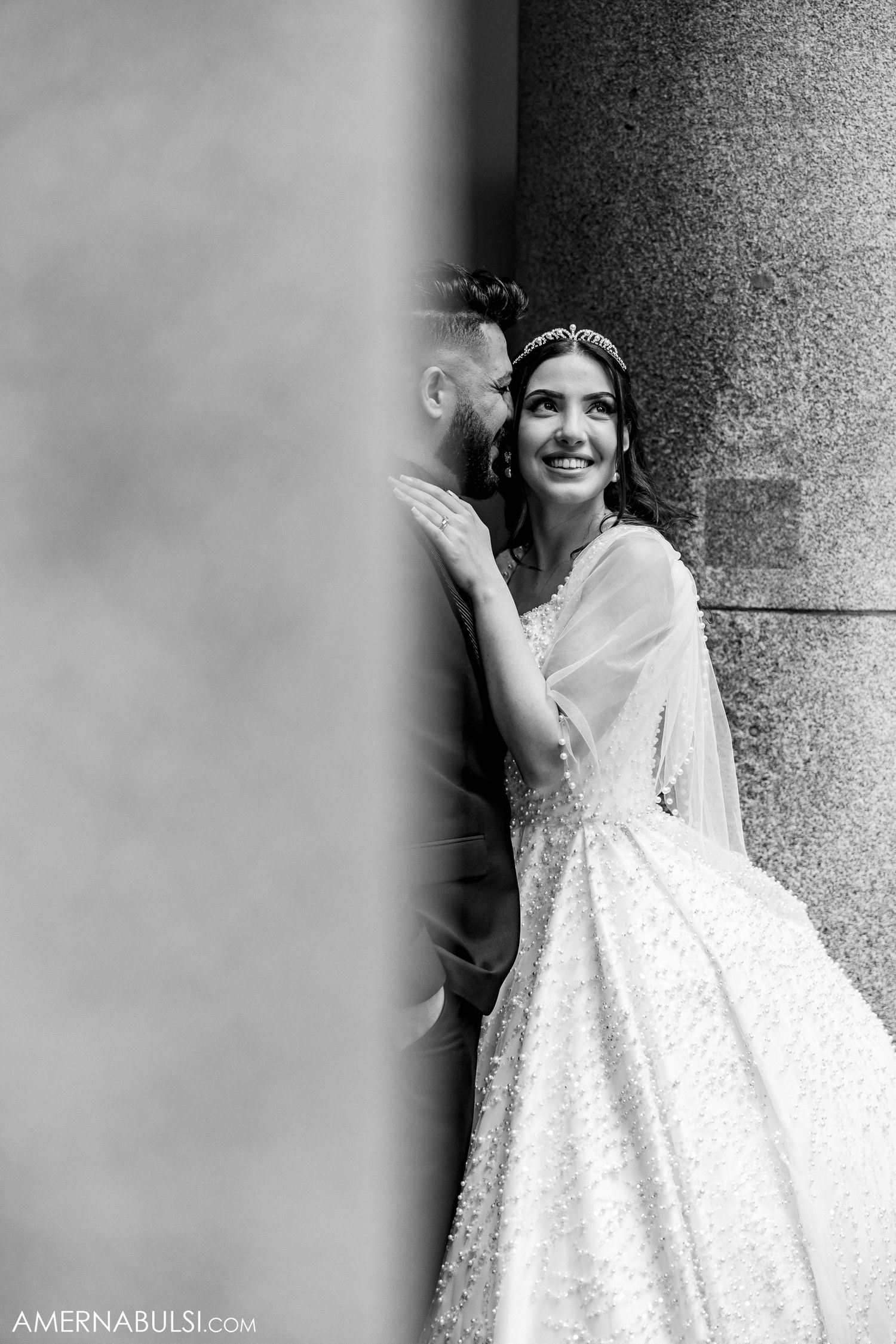 Black and white artistic wedding portrait against a textured stone column.