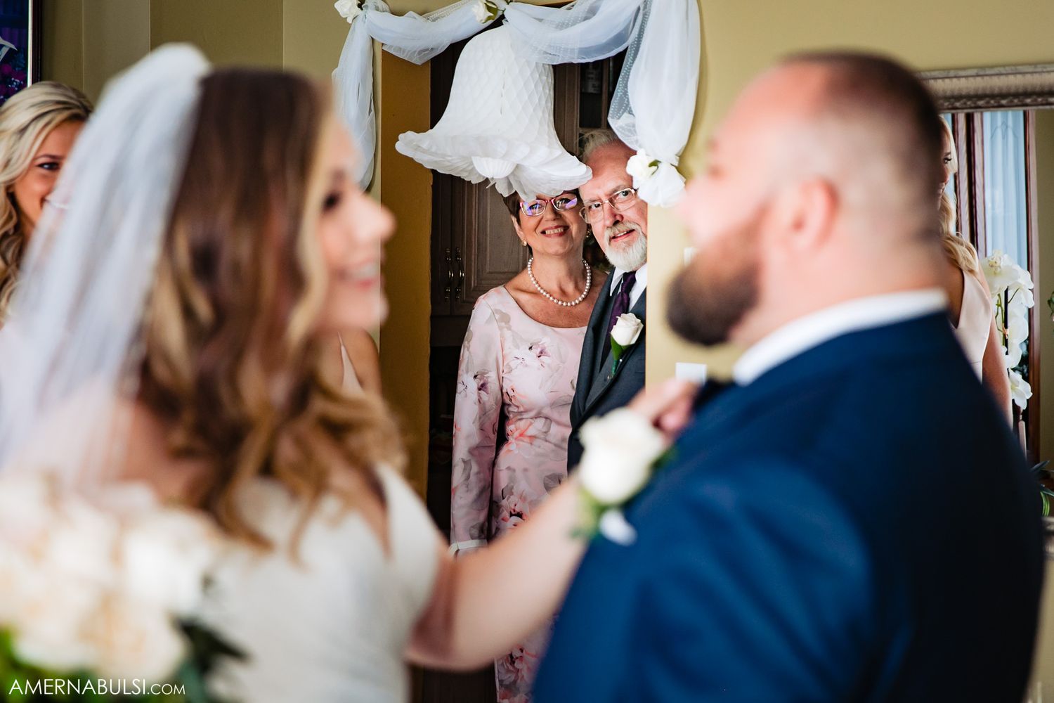 Intimate wedding moment captured through a window with soft natural lighting.
