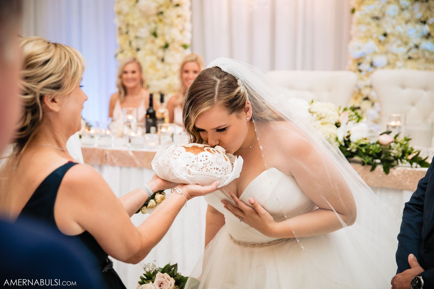 Wedding celebration with floral wall backdrop as guests share joyful moments during reception.
