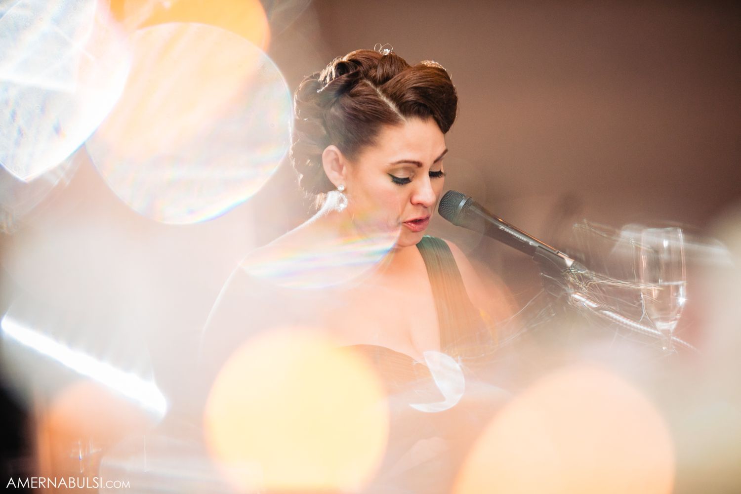 A bride in a white gown is photographed through soft bokeh lighting creating a dreamy romantic effect.