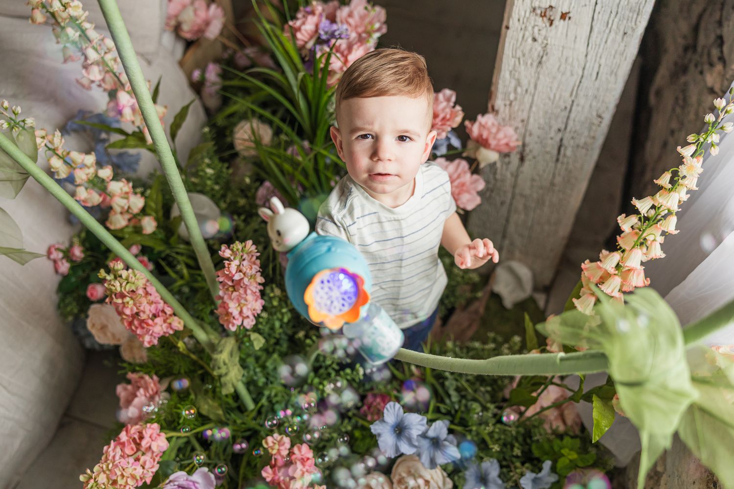 A child exploring a whimsical garden setting filled with pink and blue flowers.