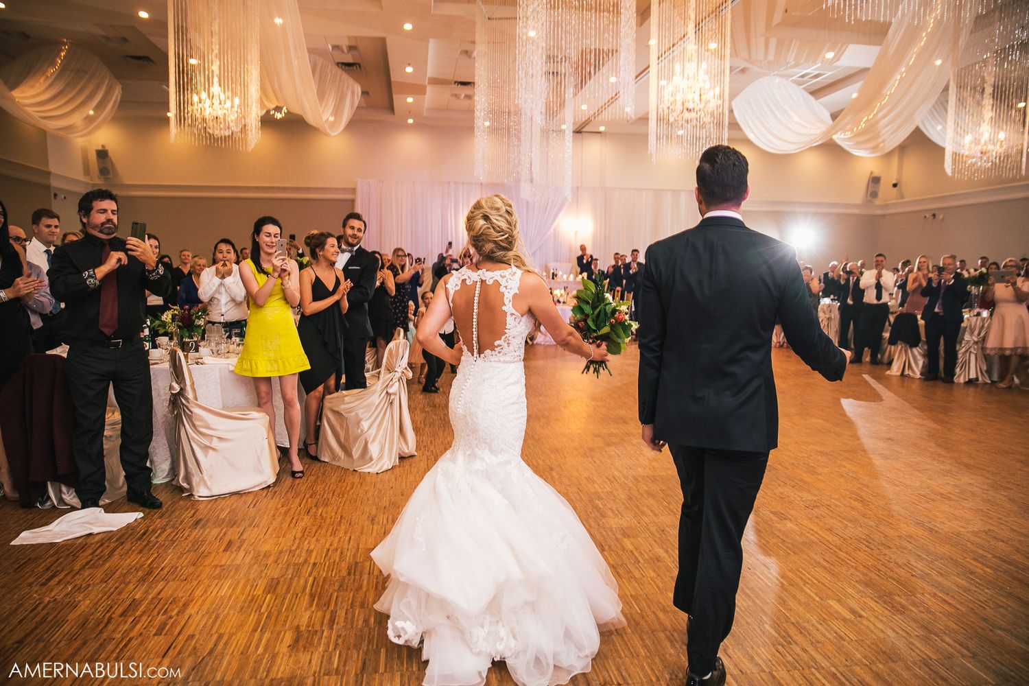 Couples dancing together at an elegant wedding reception in a ballroom with warm lighting and hardwood floors.