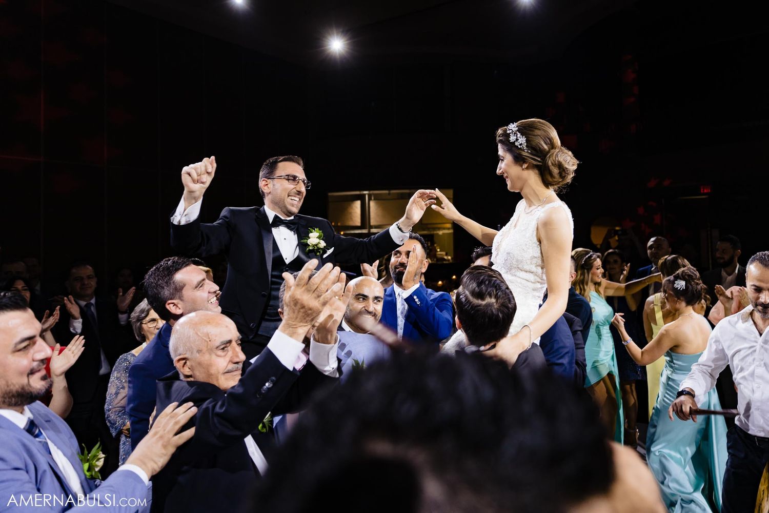 Guests lift celebrants during energetic wedding reception dancing.