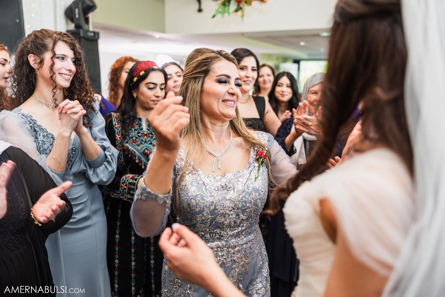 Wedding guests dancing and celebrating at an indoor reception.