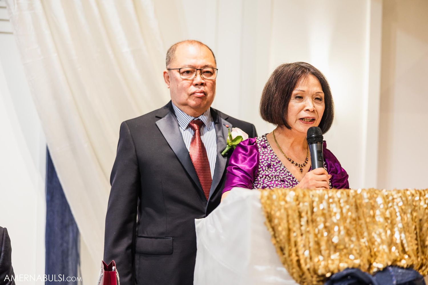 Formal speakers present at an elegant wedding reception with purple boutonniere and gold sequin decor.