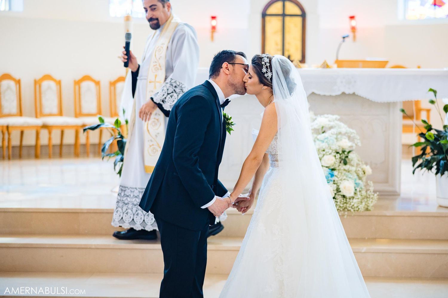 A tender moment between a bride and groom during their wedding ceremony in a bright church setting.