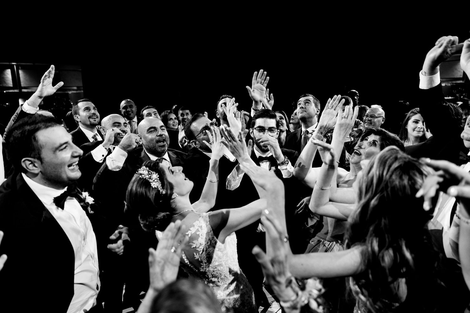 Energetic crowd with raised hands celebrates at a reception party.