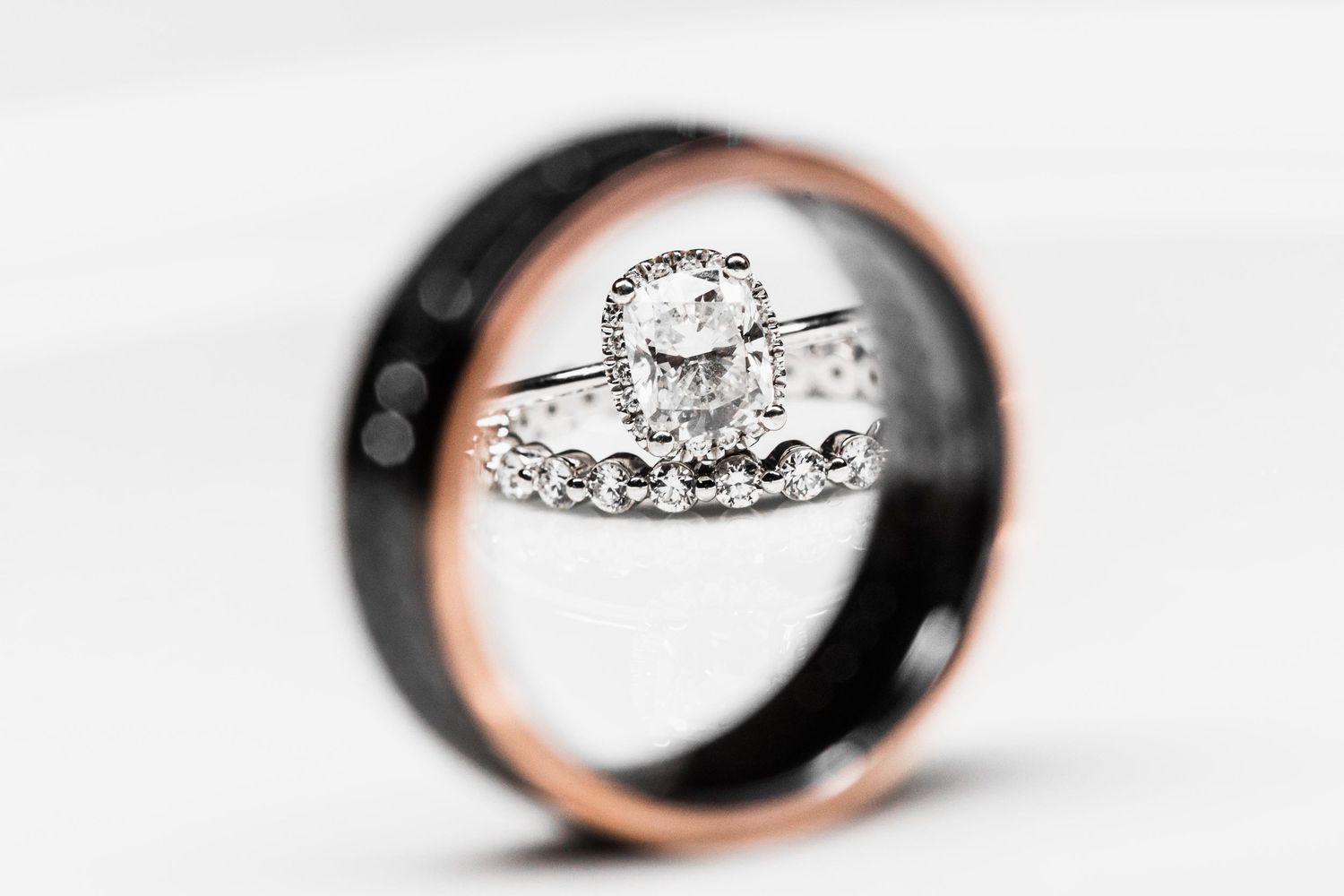 A creative wedding ring photo showing engagement ring reflection through another ring.