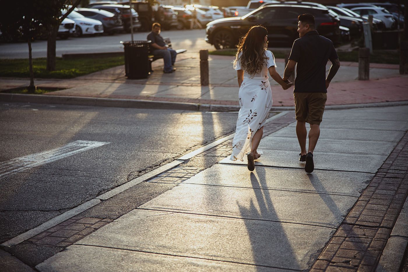 Silhouettes of people walking on a sidewalk during golden hour sunset.