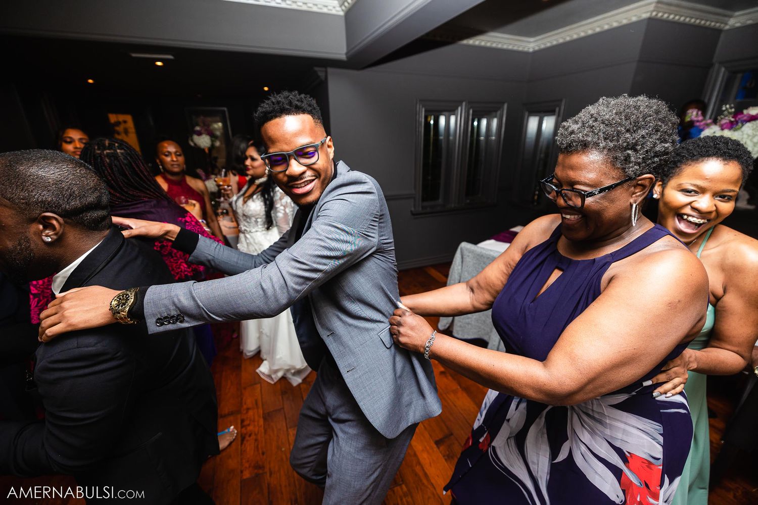 Wedding guests dancing and celebrating on the dance floor at reception.