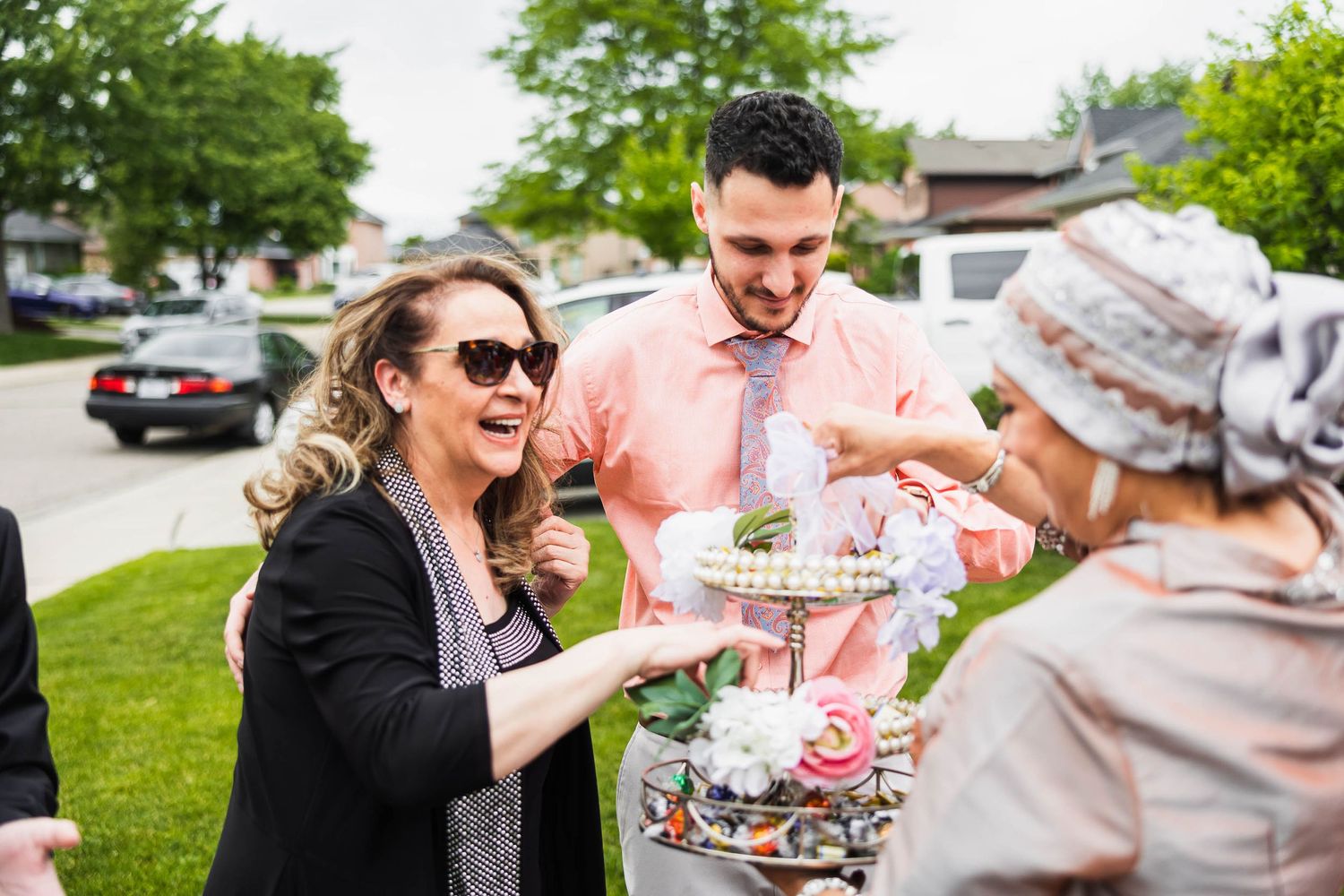 Wedding guests laugh while enjoying refreshments at an outdoor reception.