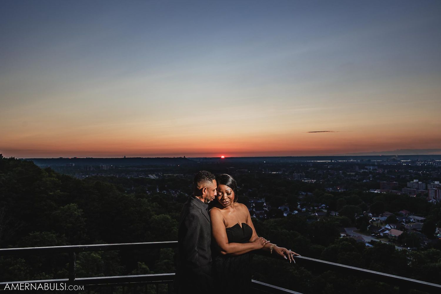 Couple in silhouette against dramatic sunset sky on observation deck.