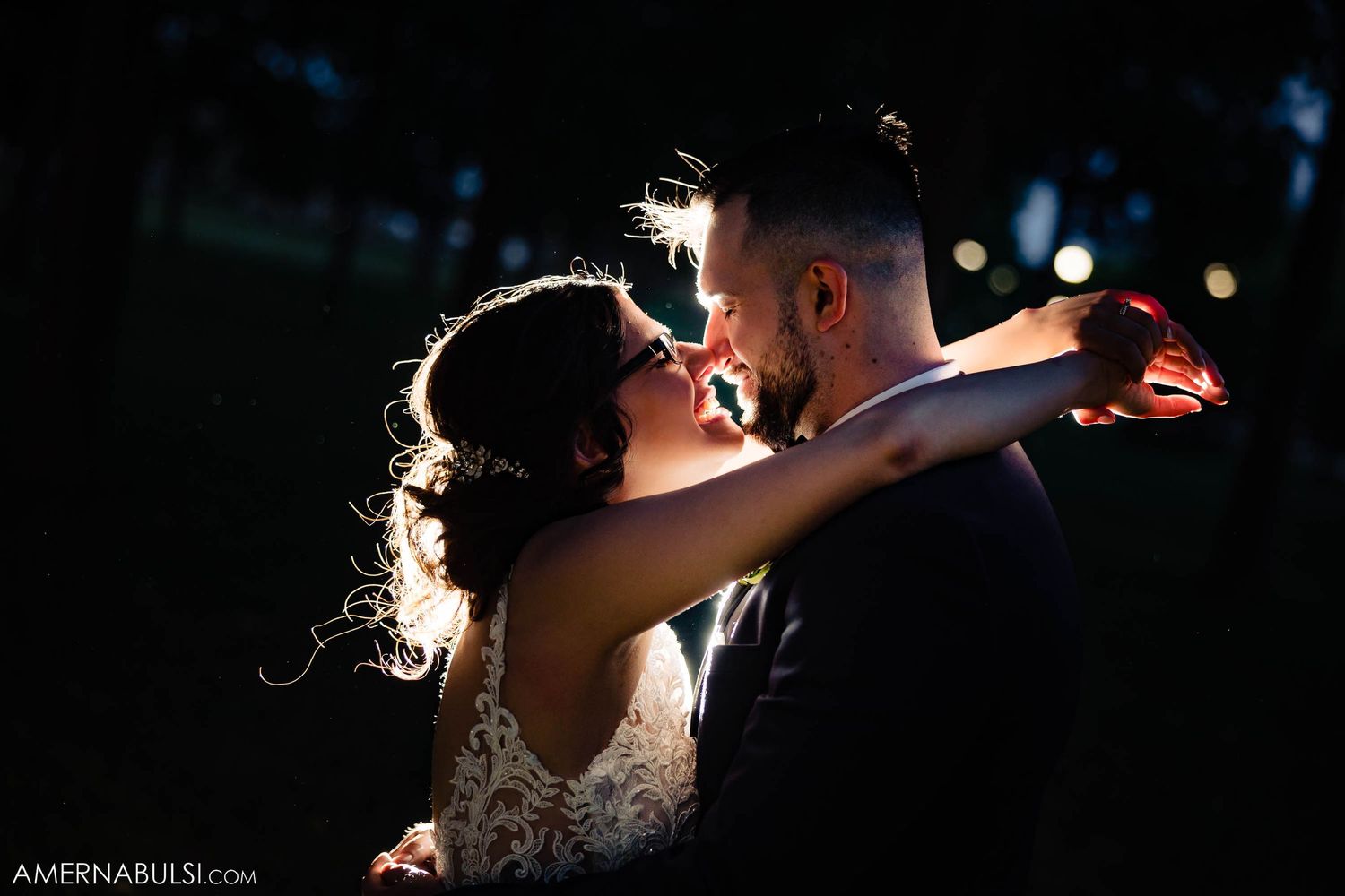 Romantic nighttime portrait of couple embracing with dramatic backlighting.