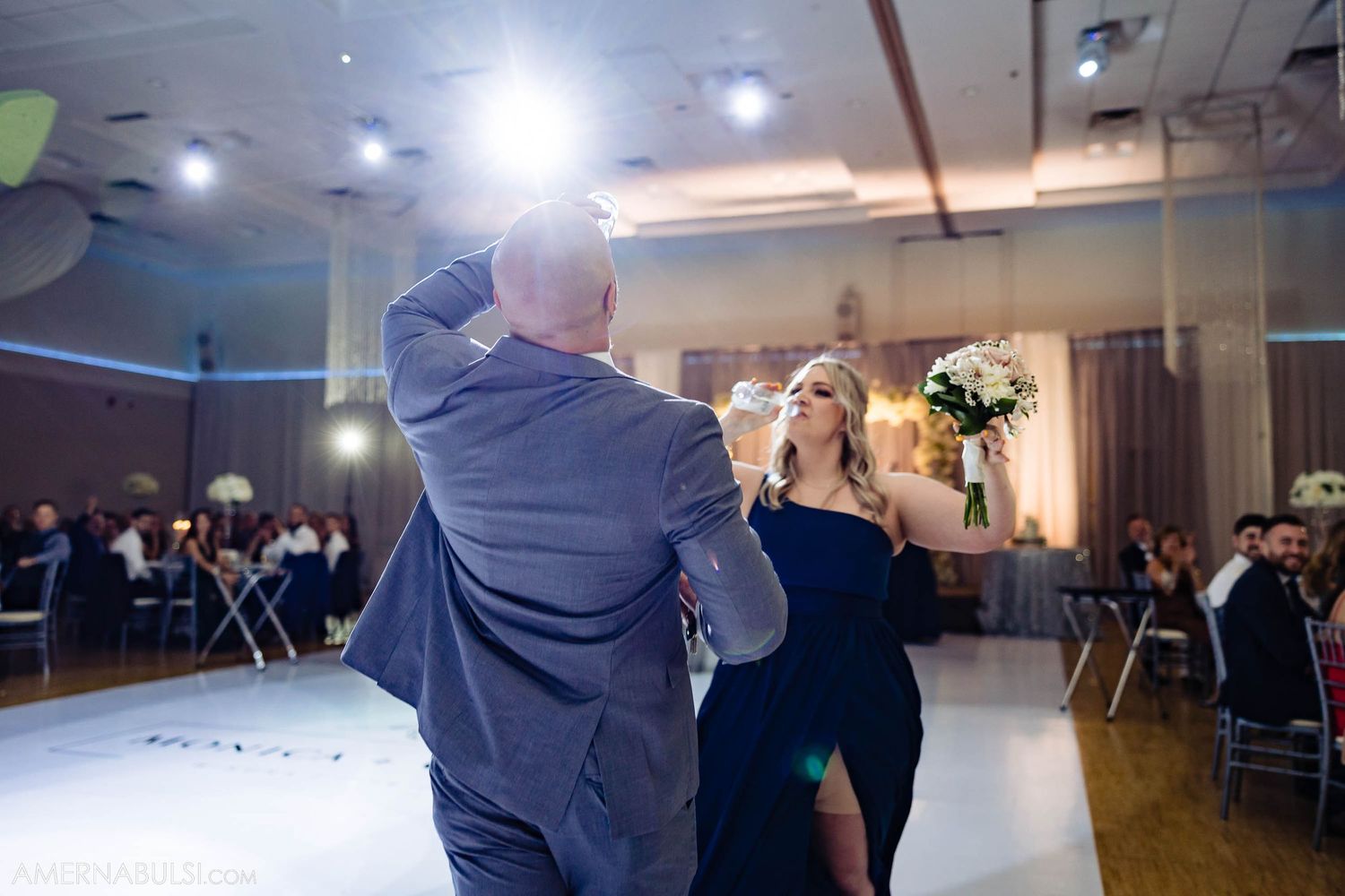 Couples dance together during an evening wedding reception with spotlights illuminating the dance floor.