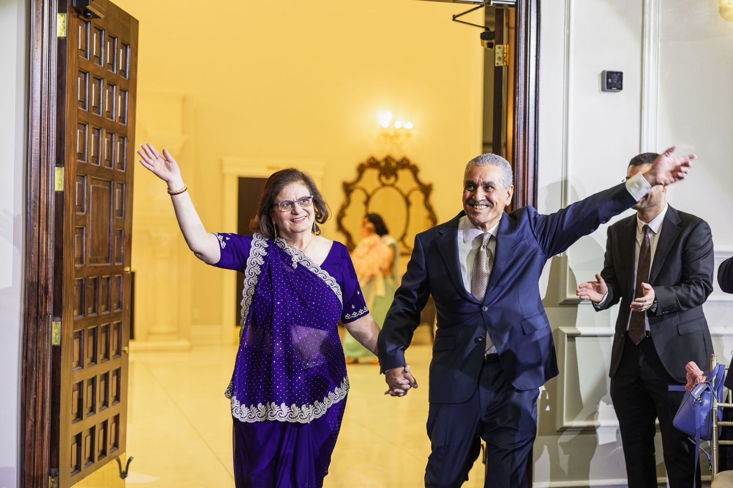 Couple makes grand entrance through wooden doors at their wedding celebration.
