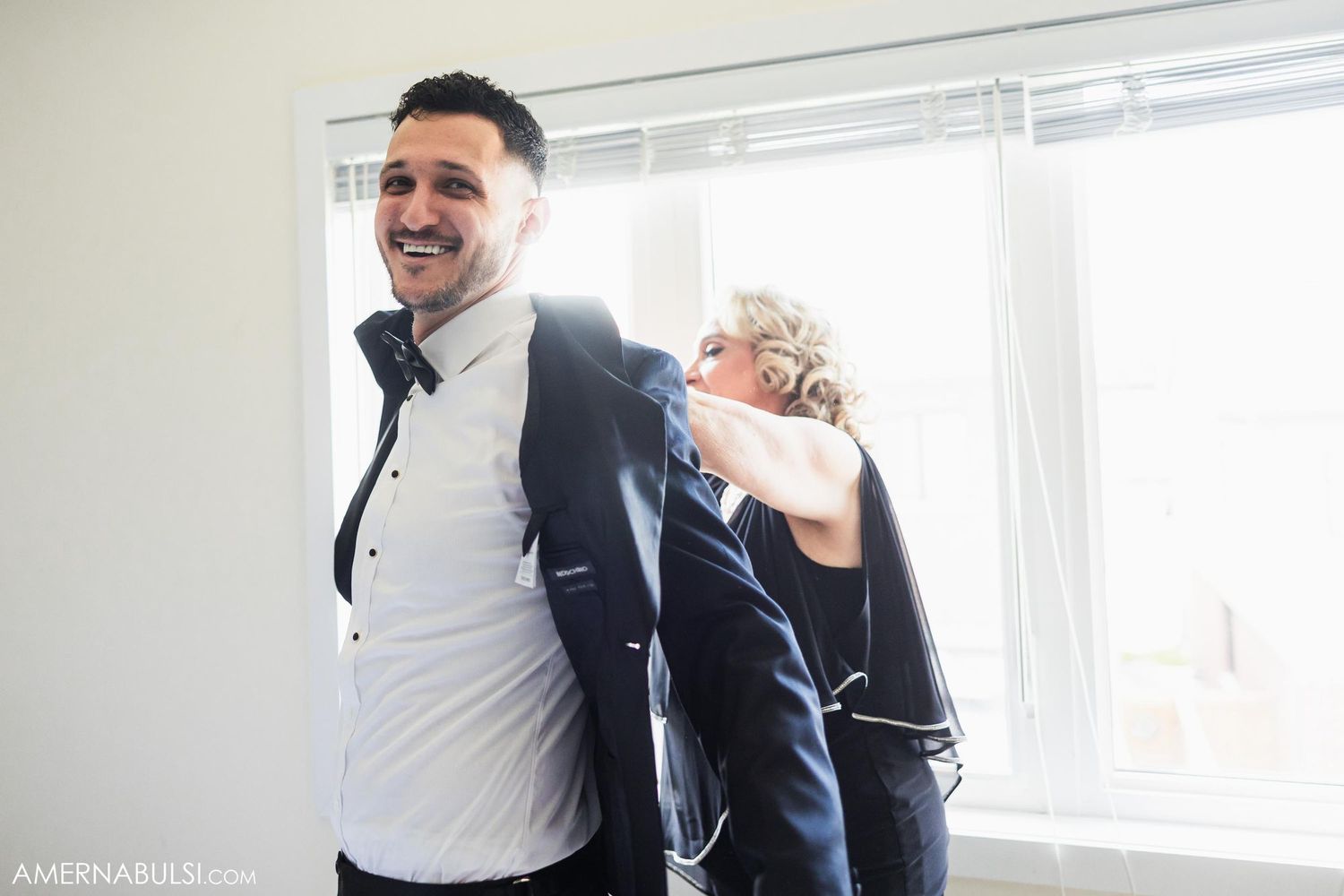 Two people sharing a lighthearted moment while getting ready for a formal event.