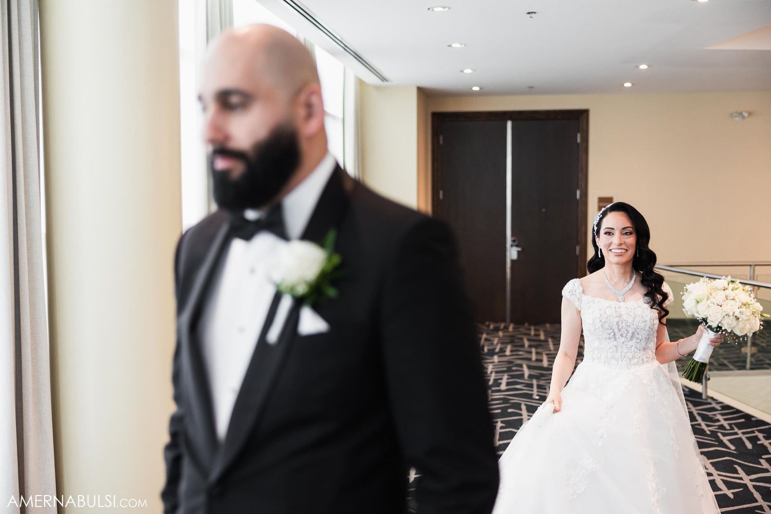 A first look wedding moment between a couple in formal attire with the bride in a white ballgown and groom in a tuxedo.