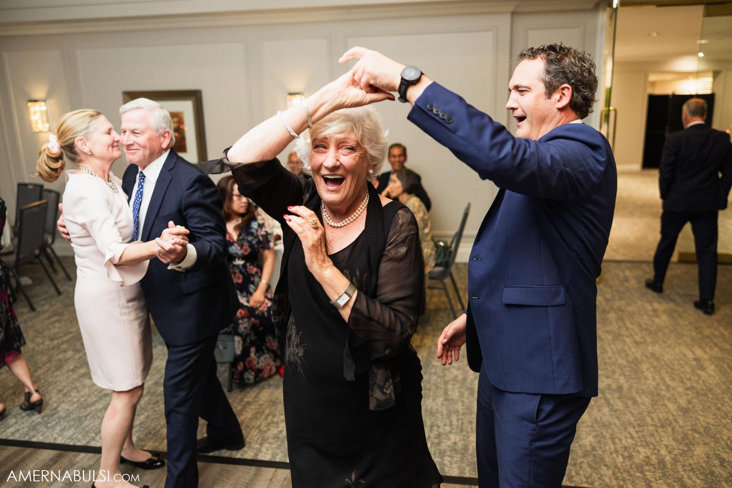 Joyful dancing at an elegant indoor wedding reception.