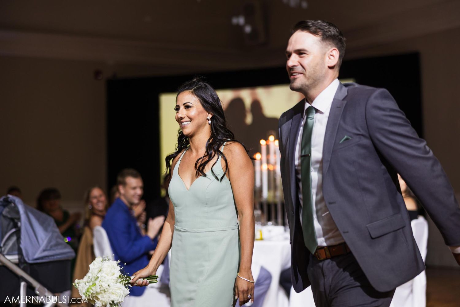 Wedding reception attendees celebrate with raised arms and excited expressions on dance floor.