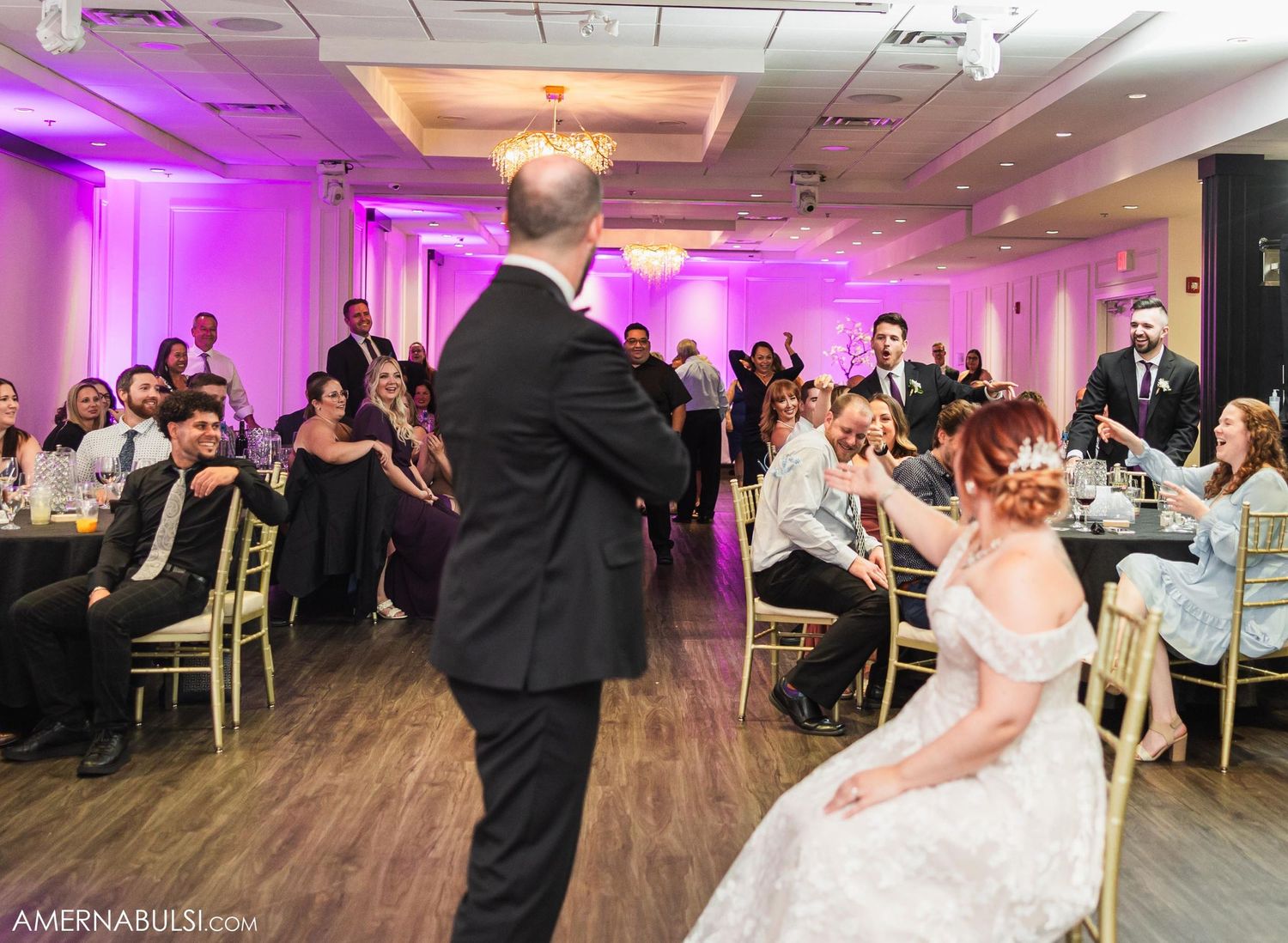 Wedding reception venue with elegantly decorated tables and purple uplighting.