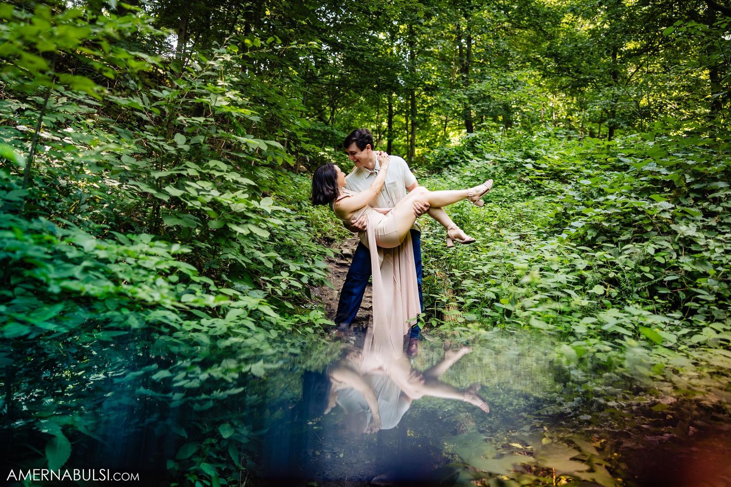 Couple embracing in ethereal forest pond setting surrounded by green foliage.