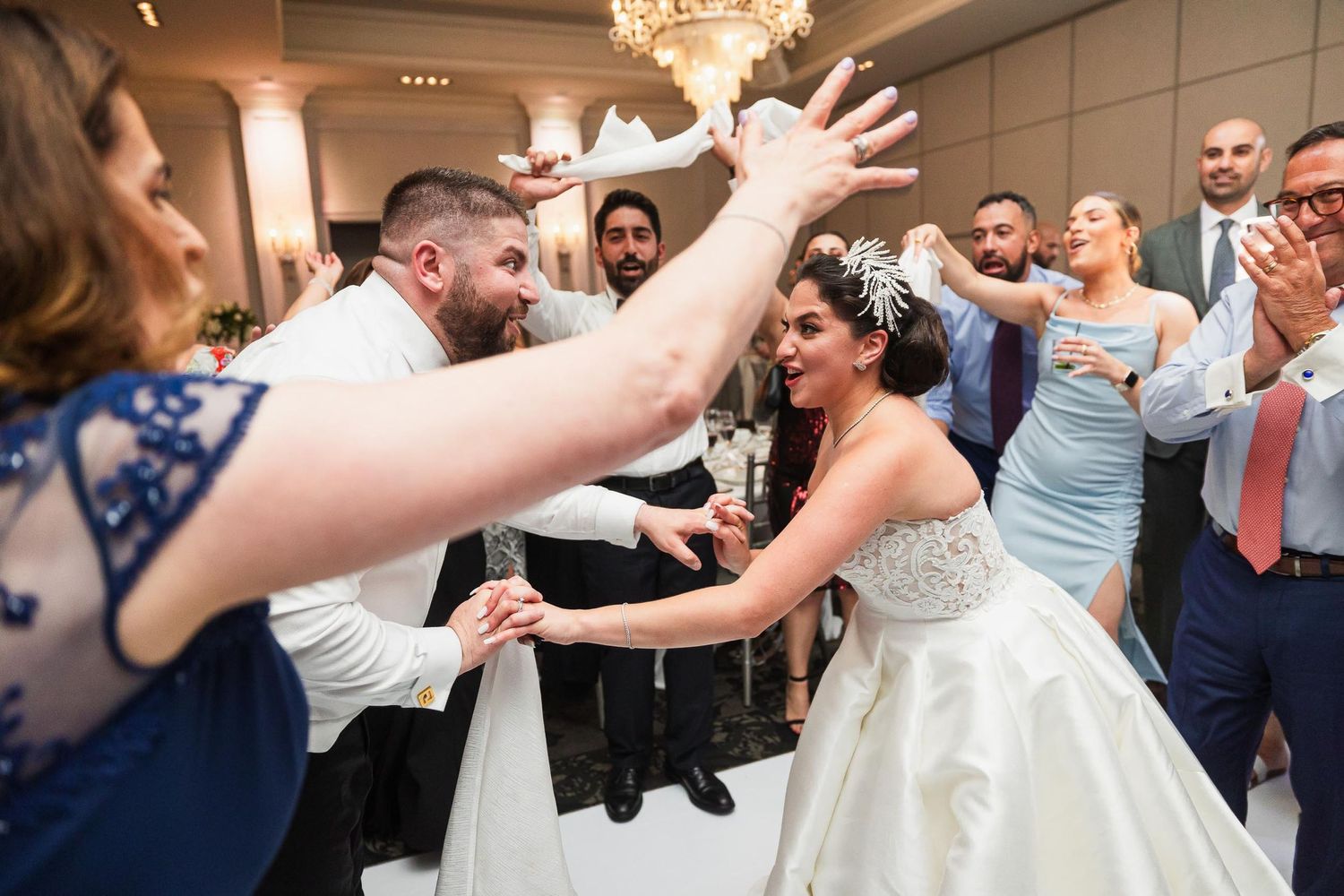 Energetic wedding reception scene with guests dancing and celebrating in formal attire.