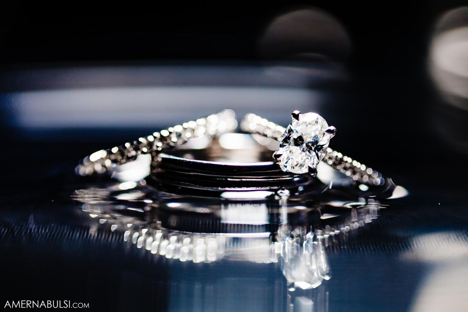 Close-up of elegant wedding rings and bands displayed on reflective surface.