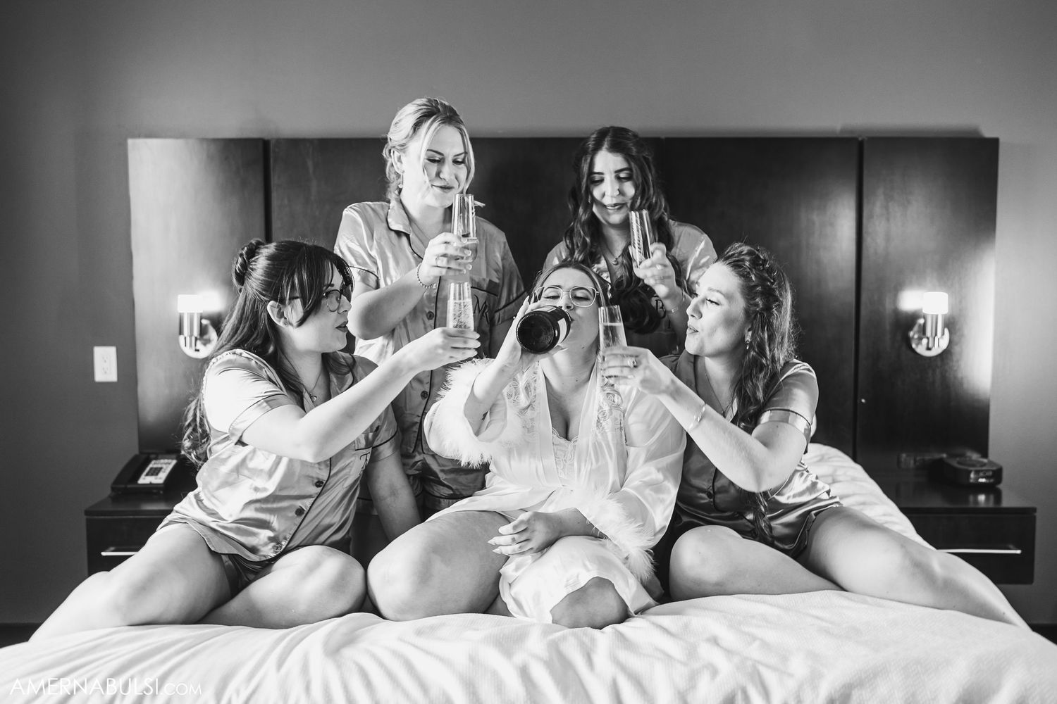 Black and white photo of friends lounging on a bed sharing laughter.