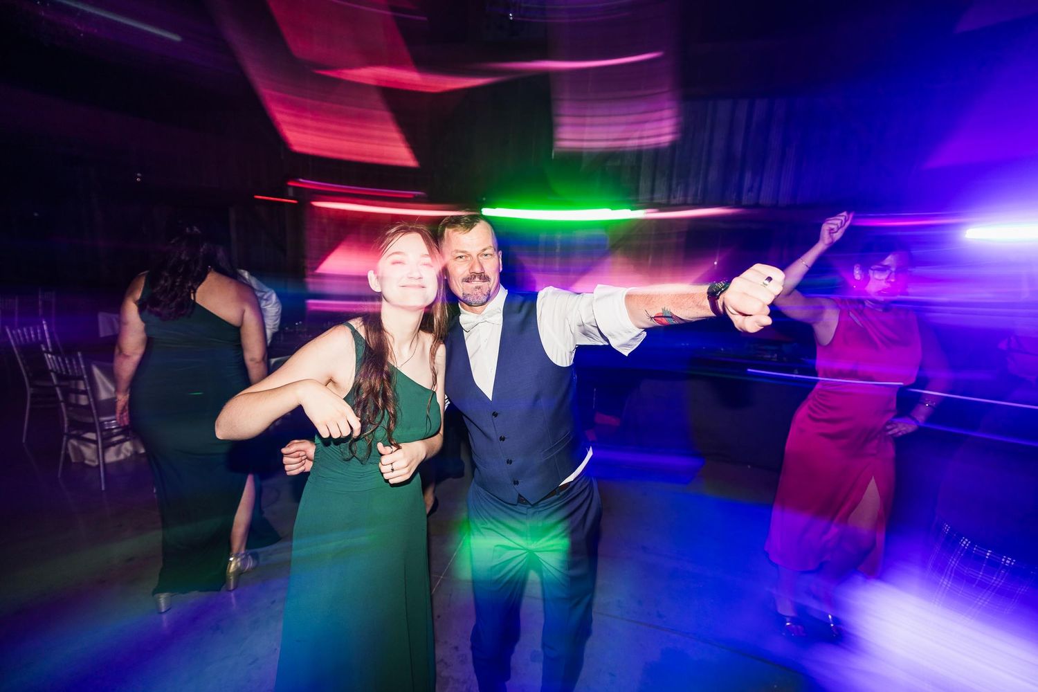 Wedding reception dance floor with colorful purple and red lighting effects.