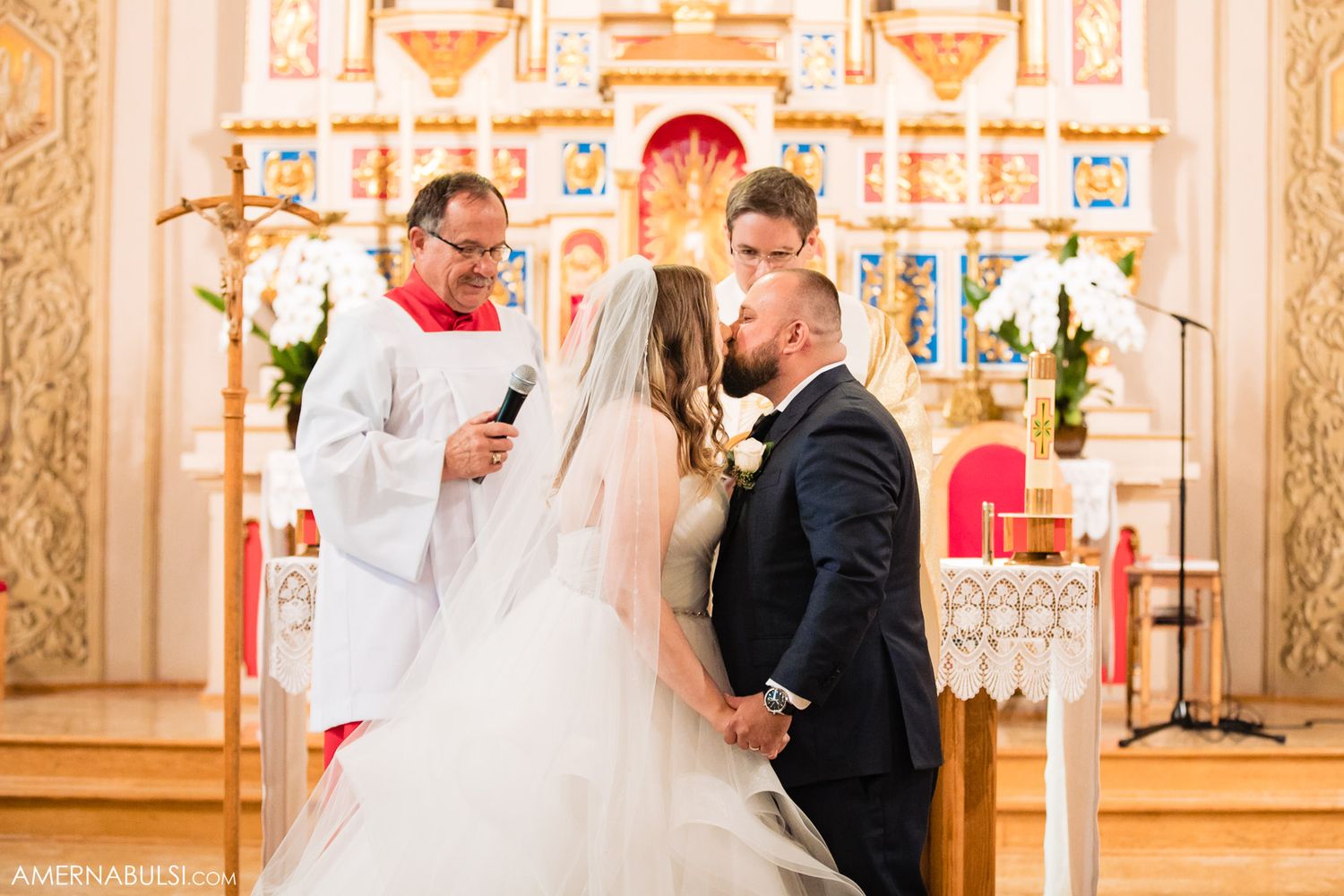Wedding ceremony taking place in an ornate church with traditional gold and white decor.