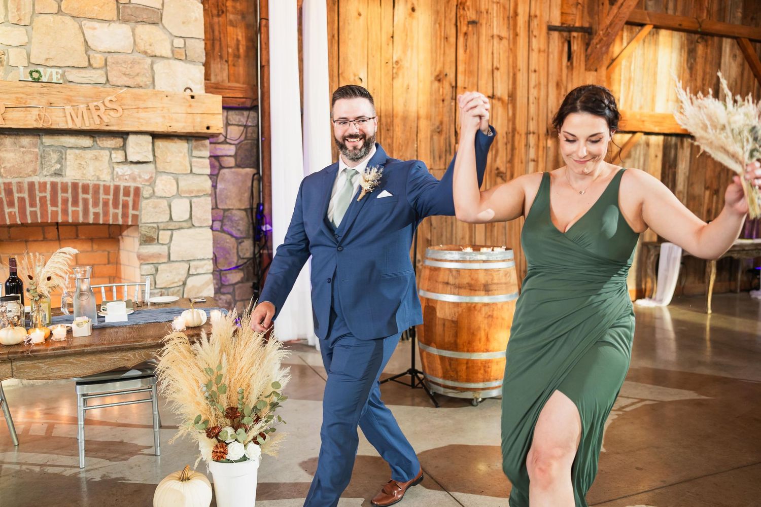 Couple dancing joyfully in a rustic venue with wooden walls and stone fireplace.