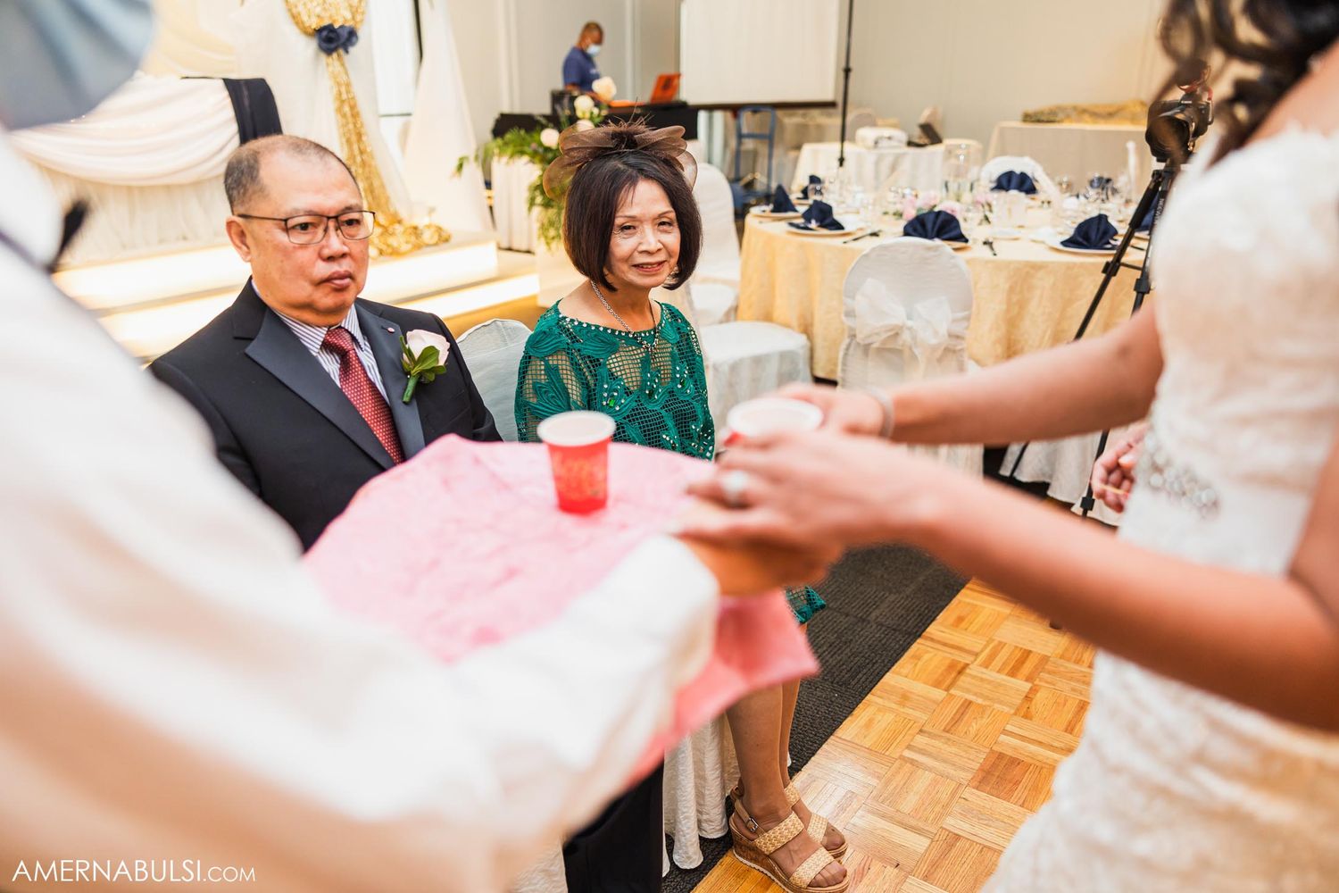 Tea ceremony celebration with guests receiving traditional drinks at wedding reception.