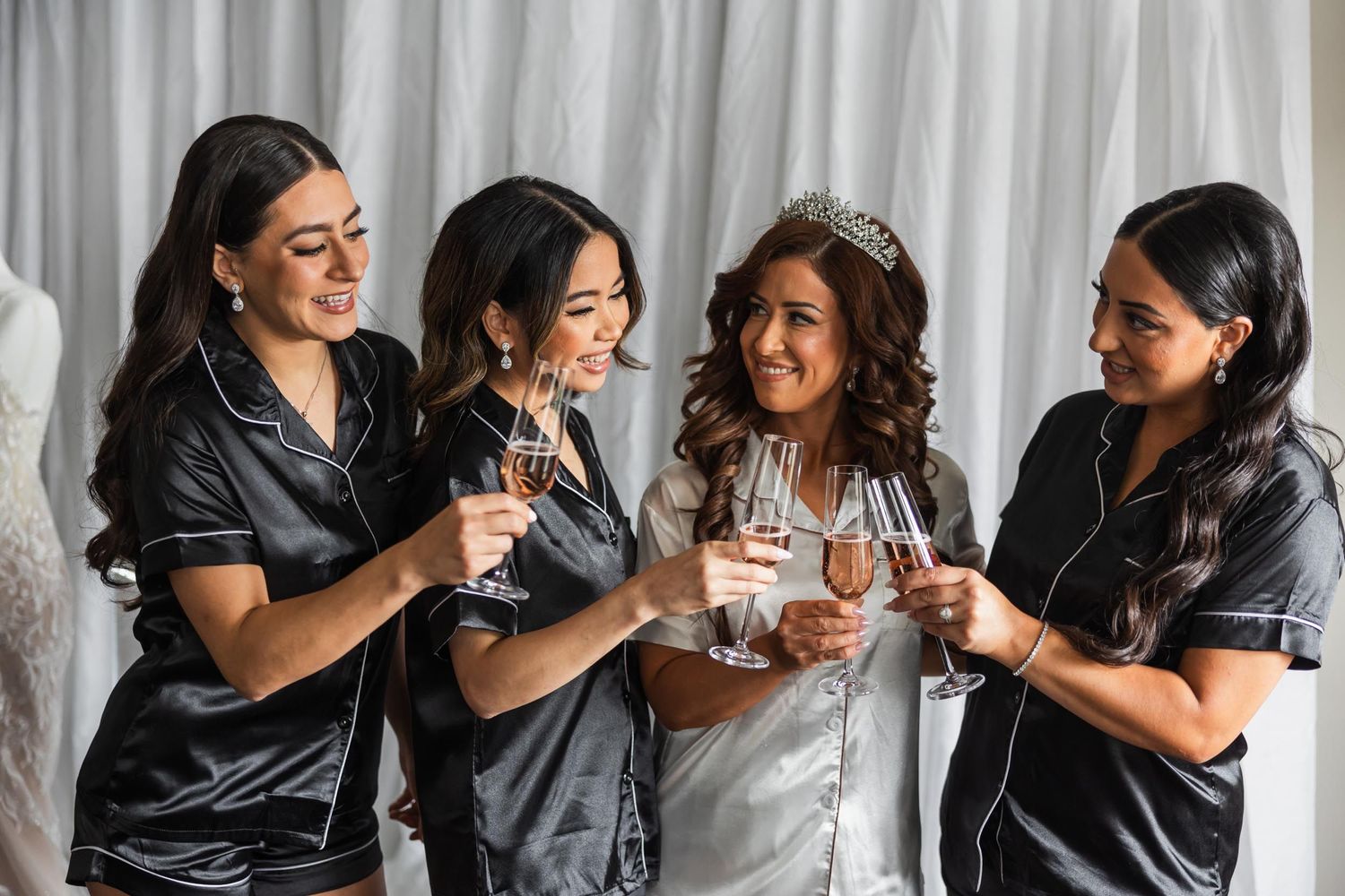 Wedding party in matching silk robes sharing champagne toast during preparation.