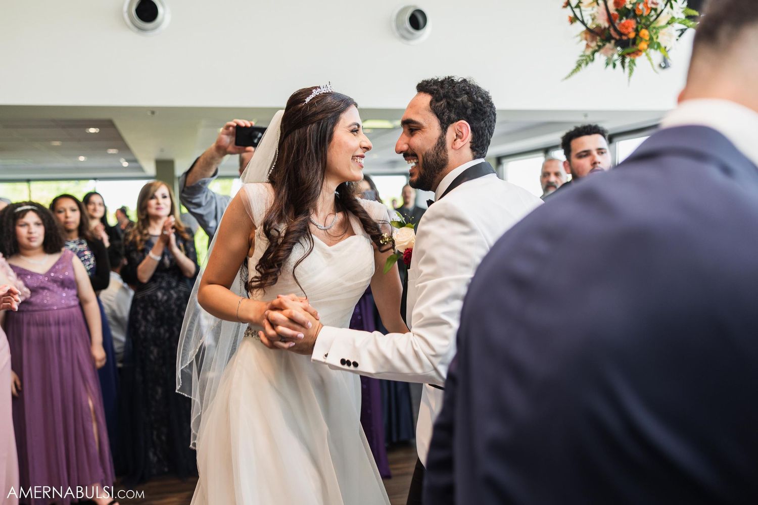 A couple shares their first dance at their wedding reception surrounded by joyful guests.