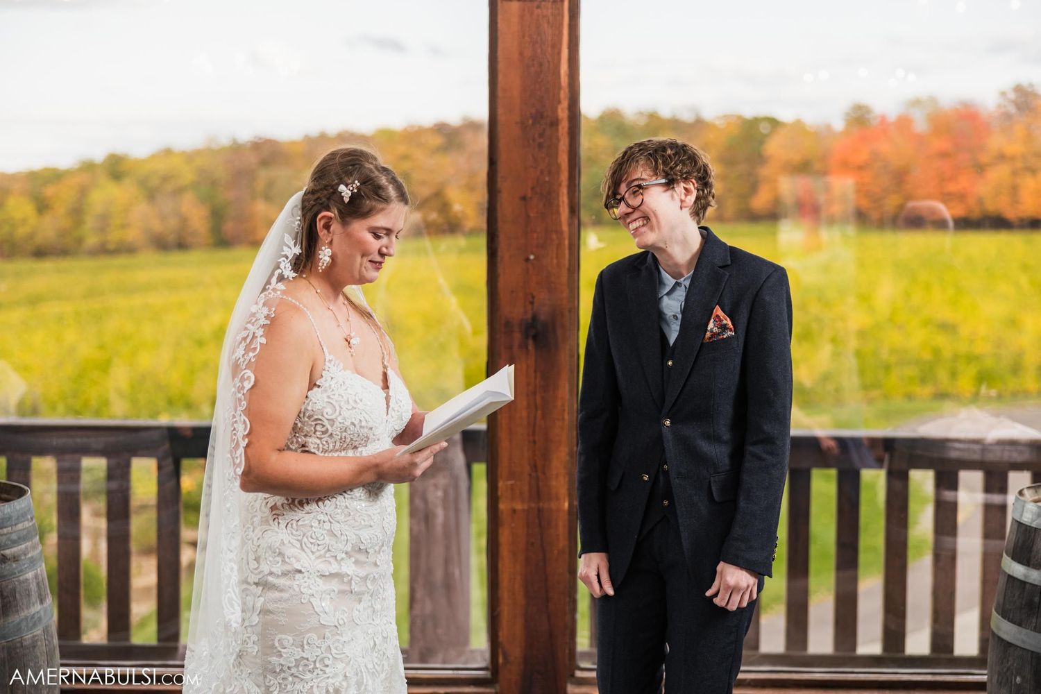 Wedding ceremony participants share written vows in front of rustic autumn scenery.