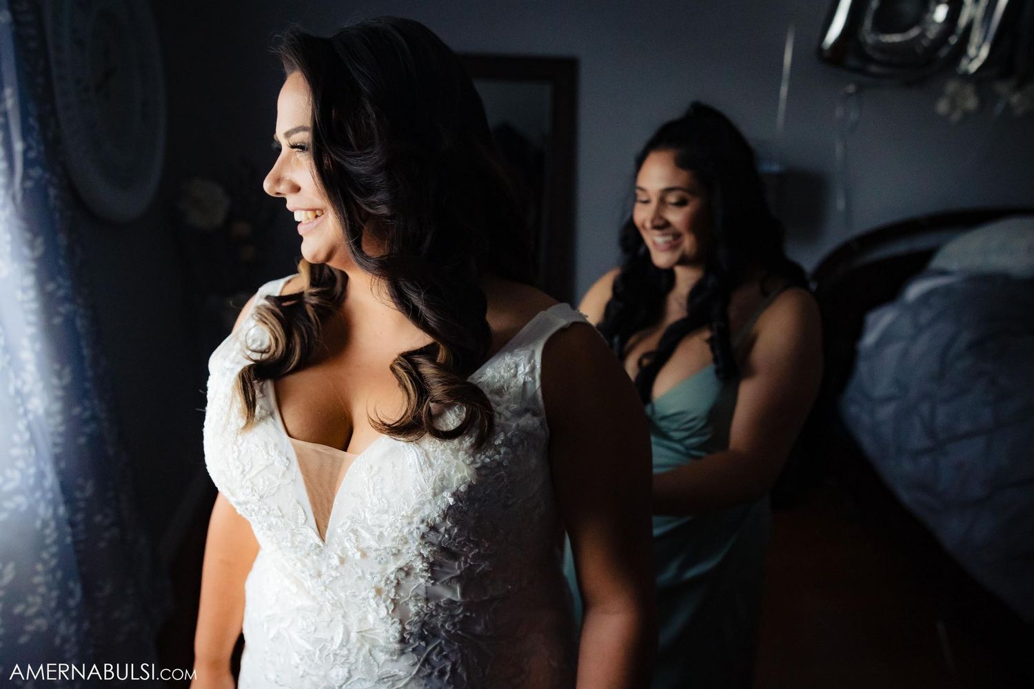 Elegant white wedding dress with intricate lace detailing in dimly lit room.