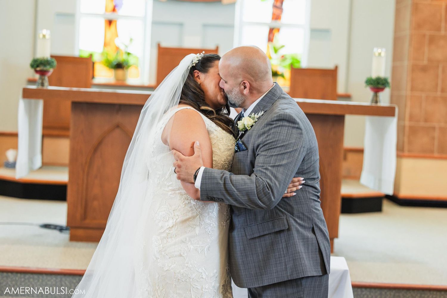 Romantic first kiss during wedding ceremony in church sanctuary.