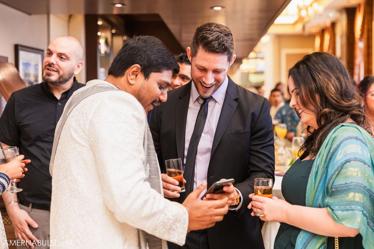 Wedding guests looking at phones during reception while dressed in formal attire.