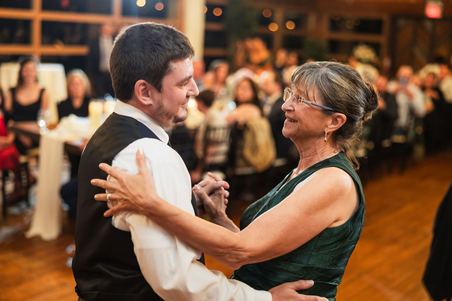 Groom and mother share an emotional first dance at a wedding reception in an elegant venue.