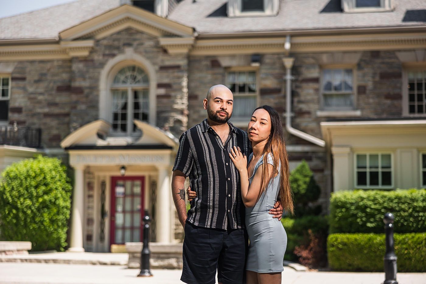 Couple poses together in front of elegant stone architecture during an engagement photo session.
