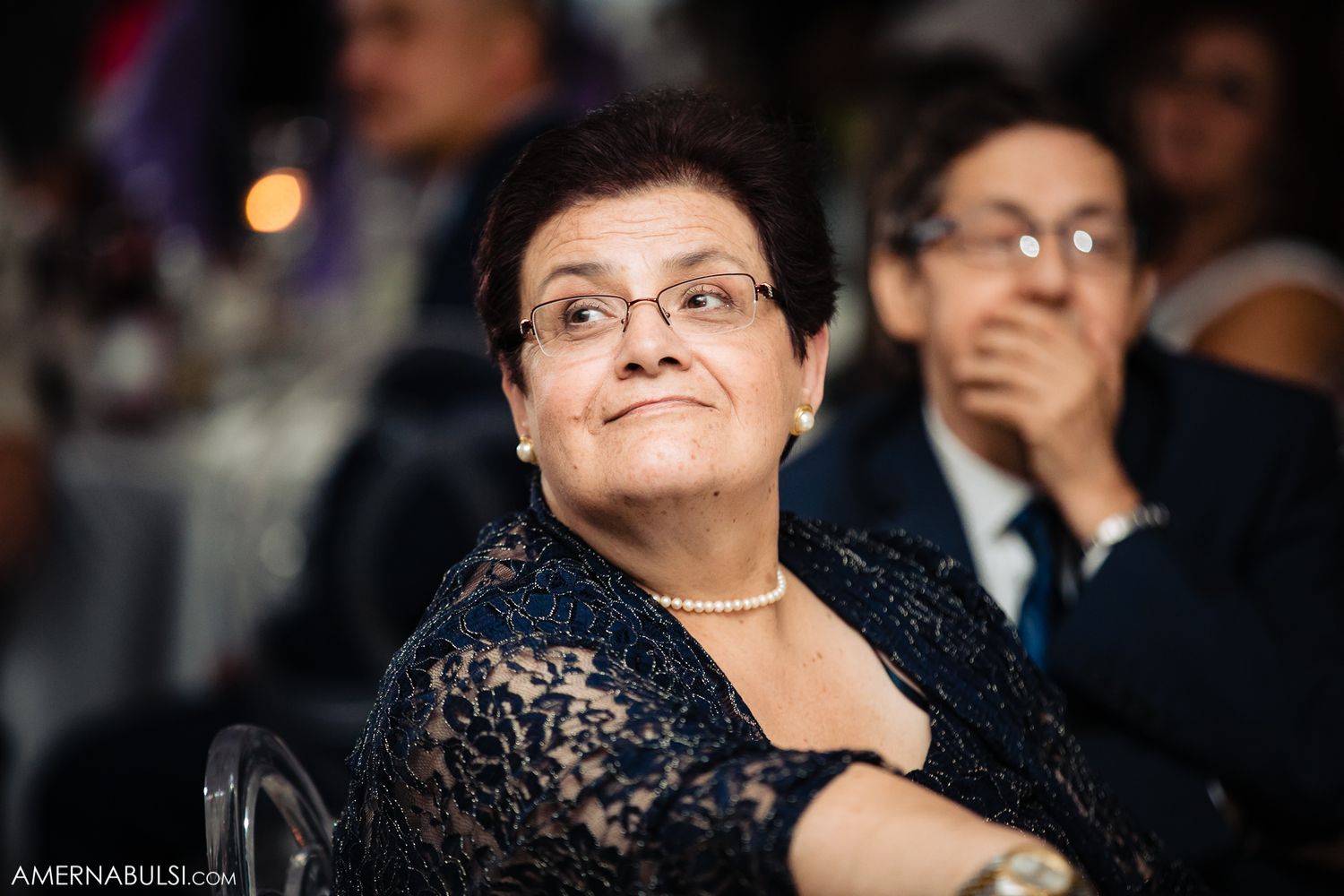 Candid reactions of formal event attendees enjoying entertainment during an evening celebration.
