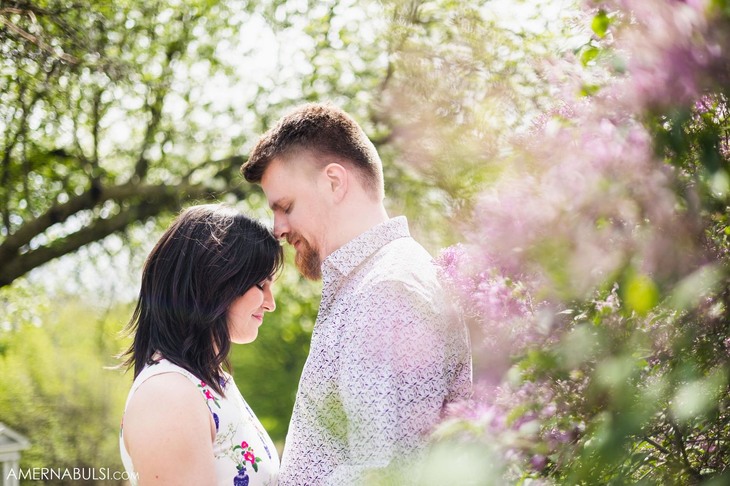 A romantic spring moment shared between a couple amid flowering branches.