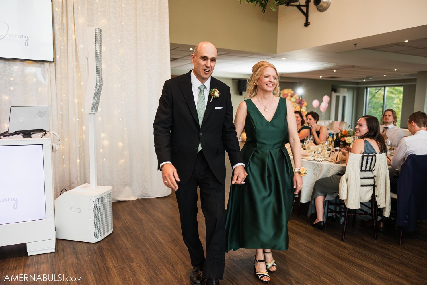 Couple makes grand entrance into wedding reception hall with hardwood floors and elegant decor.